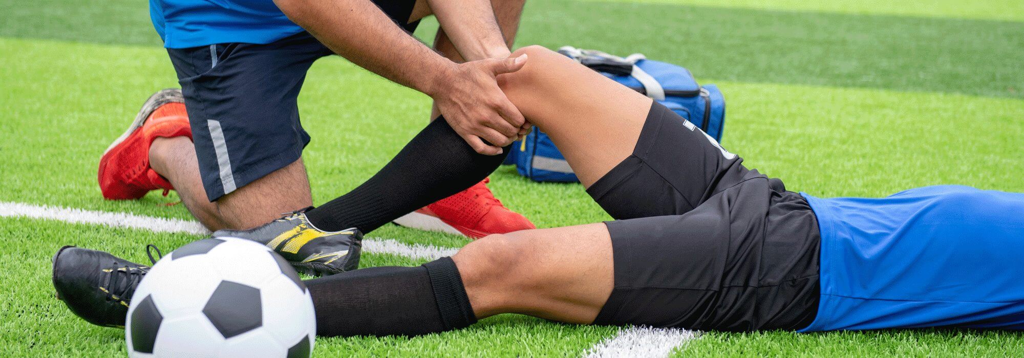 A soccer player stretching with a trainer before a game