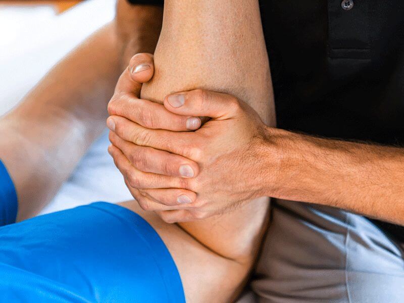 A closeup of a physical trainer working with a client's leg